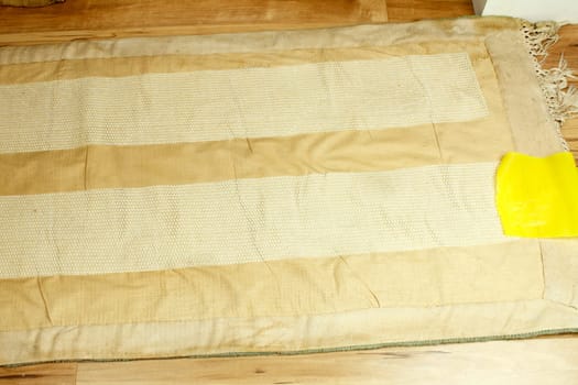 Back of a small area rug just applied anti-slip material. The yellow plastic on the right is what’s peeled off before turning the rug over to make it grip the floor..