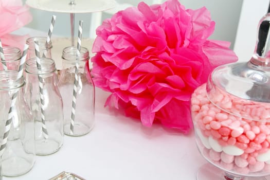 Pink pompoms, candies in a jar, and bottles with straws