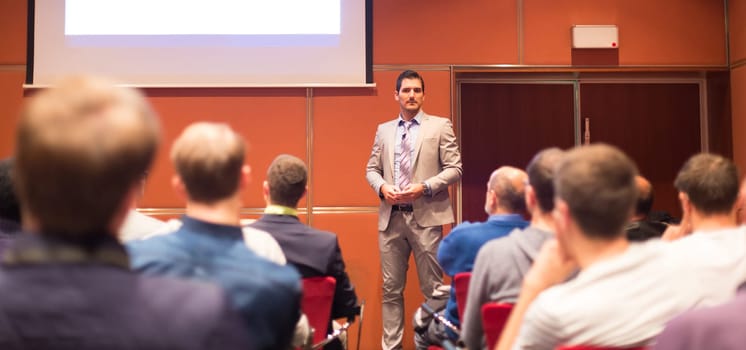 Speaker Giving a Talk at Business Meeting. Audience in the conference hall. Business and Entrepreneurship concept. Panoramic compozition suitable for banner.