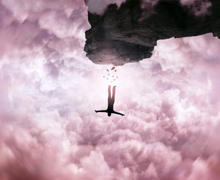 A silhouette of an young man jumping from a peak of the mountain, cliff on the sky background. Freedom and risk concept.
