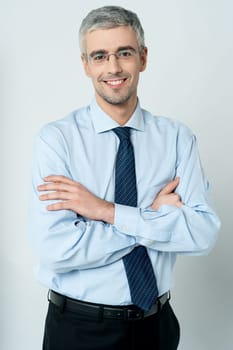Handsome young employee standing with his arms crossed