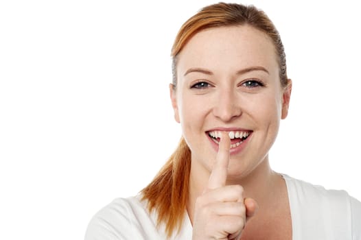 Laughing young woman showing silence gesture