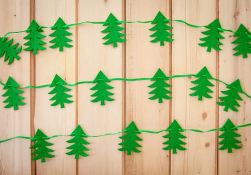 Garland with fir trees made of felt on rustic background