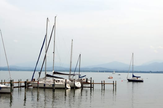 View of a pier with jetty and sailboats in Gstaad on Lake Chiemsee