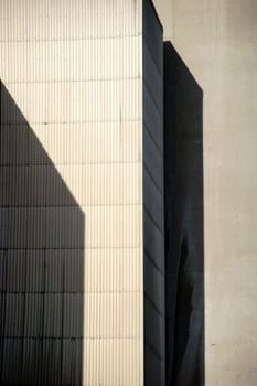 The corners and edges of an industrial building cast geometric shadows.