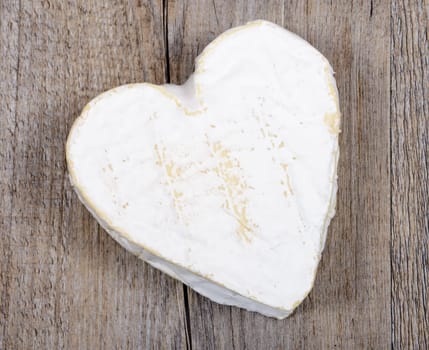 French Neufchatel cheese shaped heart on a wooden table