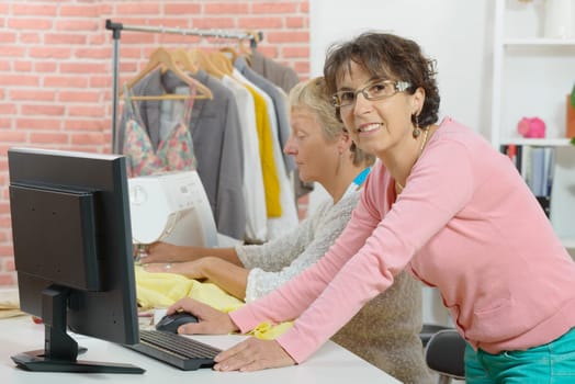 Two cheerful seamstresses working together in their fashion workshop