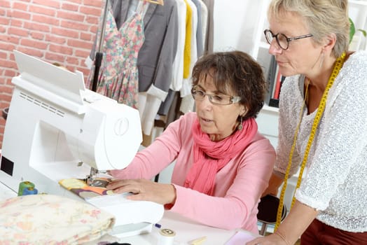 Two cheerful seamstresses working together in their fashion workshop