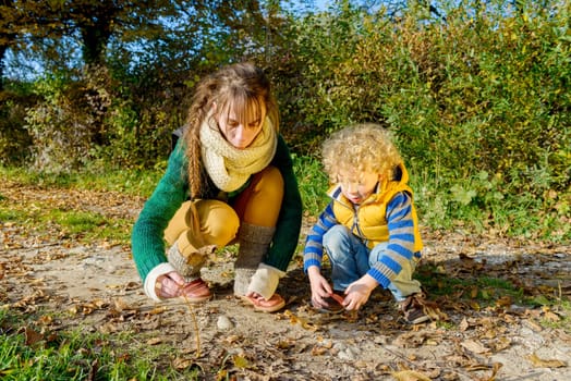 a little blond boy and his mom play outside, an autumn day