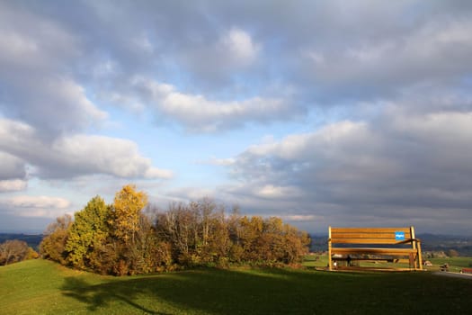 Autumnpanorama with a large wooden bench in the Allgäu