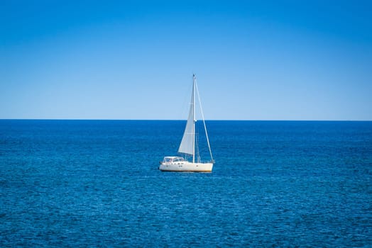 Small sailboat on the blue ocean in daylight
