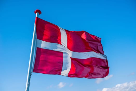 Danish flag in the wind on blue background