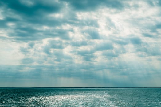 Clouds over the ocean with sunbeams in daylight