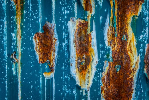 Rusty metal surface with blue paint and nails