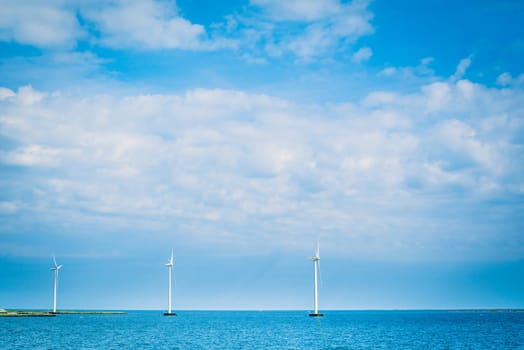 Windmills on a row in the blue ocean