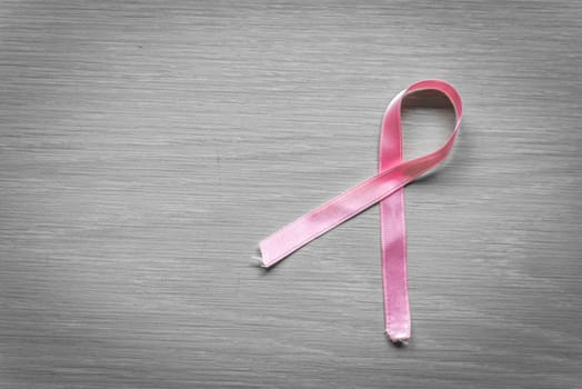 Breast cancer ribbon in pink on wooden surface