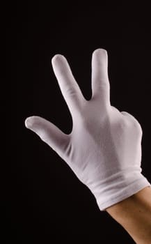 Male hand with white gloves counting number three