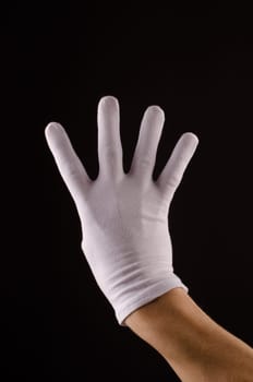 Male hand with white gloves counting on a dark background