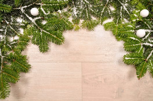 Green twigs with snow on a wooden background