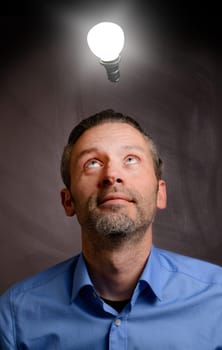 Business man looking up to a light bulb, having a great idea