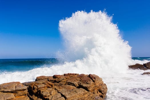Ocean wave crashing rocky shoreline exploding white water power