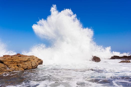 Ocean wave crashing rocky shoreline exploding white water power