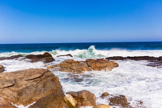 Ocean wave crashing exploding along rocky shoreline exploding white water power