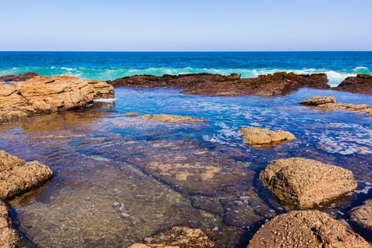 Ocean wave water into rocky coastline tide pools