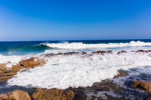 Ocean wave crashing exploding along rocky shoreline exploding white water power
