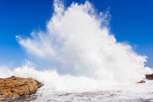 Ocean wave crashing rocky shoreline exploding white water power