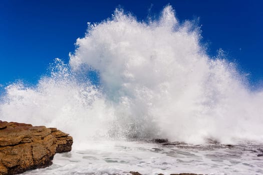 Ocean wave crashing exploding along rocky shoreline exploding white water power