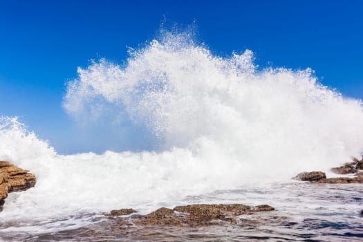 Ocean wave crashing exploding along rocky shoreline exploding white water power