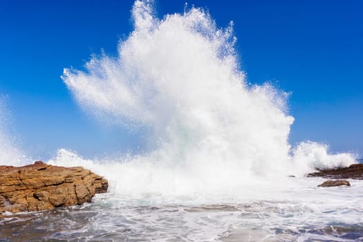 Ocean wave crashing rocky shoreline exploding white water power