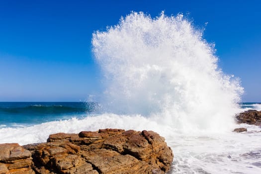 Ocean wave crashing rocky shoreline exploding white water power
