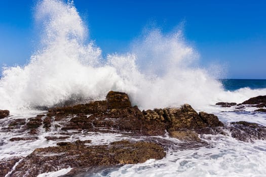 Ocean wave crashing rocky shoreline exploding white water power