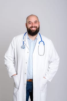 young bearded doctor in white coat in front of gray background