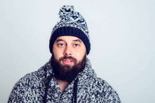young bearded man in winter dress in frontof gray background
