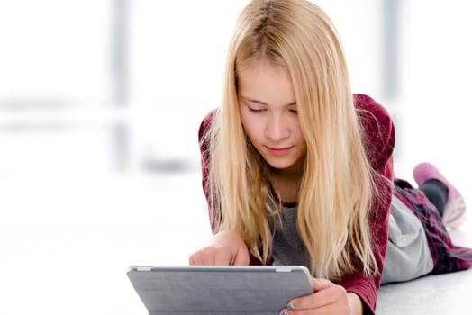 nice blond girl with tablet pc lying on the floor