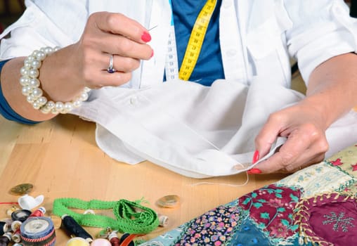 A woman sews a button on a shirt