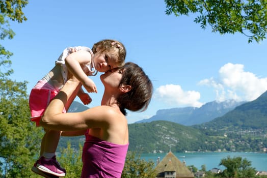 a beautiful mom is a hug to her daughter in nature