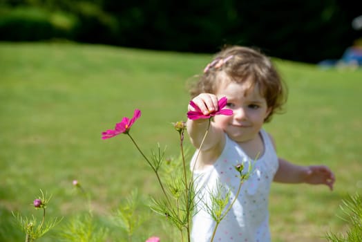 a pretty little girl playing with flowers in the garden