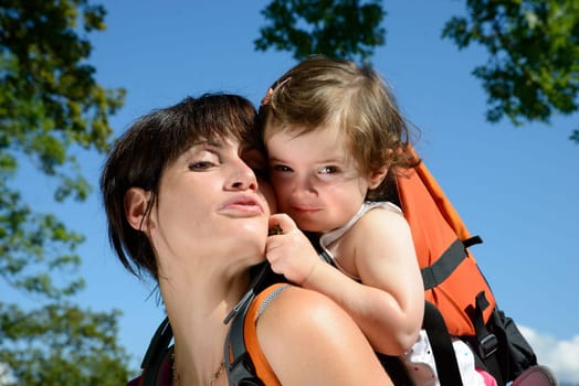 a little girl in a baby carrier walks with his mom