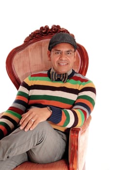 A happy Hispanic man with a bowtie and cap sitting relaxing in a armchair.smiling, isolated for white background..