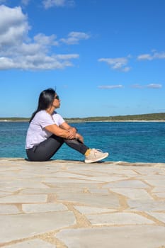 Young Woman Sitting And Enjoying The View Of The Sea in Colonia San Jordi, Balearic Islands, Majorca, Spain.