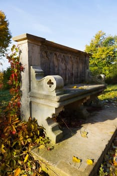 Stone bench covered with wild wine in autumn colours