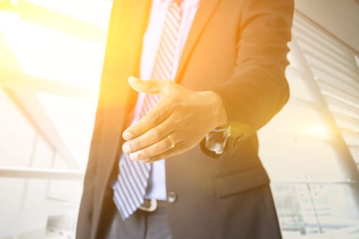 Close up business people hand offering handshake, golden sunlight from background, sunrise or sunset business.