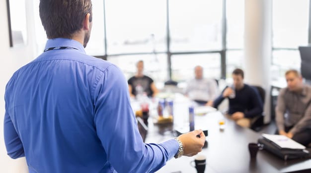 Business man making a presentation at office. Business executive delivering a presentation to his colleagues during meeting or in-house business training, explaining business plans to his employees.