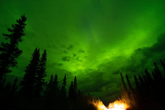The Northern Lights emerge through the clouds in remote Alaska