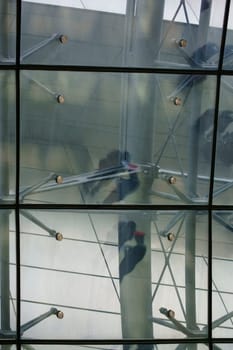The abstract reflection of ticket inspectors,conductors and travellers in the roof construction of a railway station.