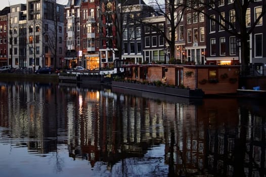Amsterdam,Netherlands - December 29,2014: A canal or side canal in Amsterdam with colorful houses reflected in the water in the early morning of December 29,2014 in Amsterdam.